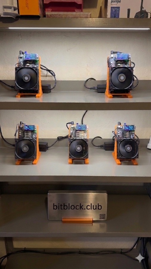 Fuenf NerdAxe++ Miner auf einem Regal, davor ein bitblock.club Schild
